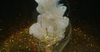 Buhar akışı. Odaklanmış çelenk aydınlatması. Beyaz duman rengi boya akışı. Işıldayan sıvı sıçrama altın ampul soyut siyah arkaplan.