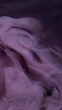 Dikey video. Renk buharı. Bulut mürekkebi. Odaklanmamış mor simli su egzozu soyut koyu siyah arkaplan üzerindeki ışıltılı dokuyu söndürür..