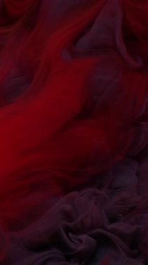 Dikey video. Su altı boya damlası. Mürekkep arkaplanı. Odaklanmamış kırmızı mor renkli bulut dalgası soyut sanatta yayılan kimyasal sıvıyı karıştırıyor.