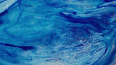 Parıltı karışımı. Parlak, ışıl ışıl bir doku. Odaklanmamış mavi pembe renkli simli boya parçacıkları soyut sanat arka planına sıvı dökülmüş..