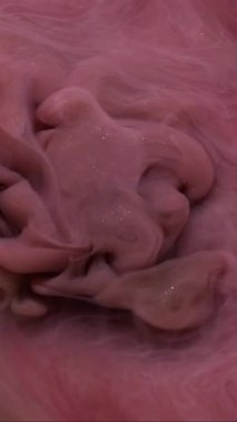 Dikey video. Bulut dalgası. Boya karışımı. Odaklanmamış pembe renk su dokusu akrilik buhar sıvısı soyut koyu siyah sanat arka planında yüzüyor..