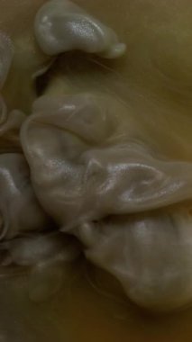 Dikey video. Sigara arkaplanı. Buhar bulutu. Odaklanmamış sarı bronz mor renk akrilik soyutlamada büyüyen suda boya sıçratıyor..