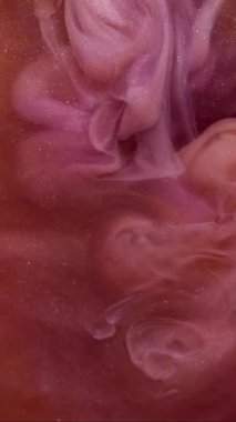 Dikey video. Dönen sis. Parıldayan sanat. Odaklanmamış turuncu mor renkli boya soyut arka planda yayılan su dumanı akışında dönüyor..
