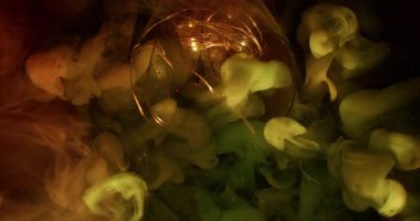 Su altı dumanı. Bulanık ışık parlıyor. Aydınlatılmış cam çelenk soyut renk sıçraması. Koyu yeşil arka planda turuncu yeşil bulut akışı.
