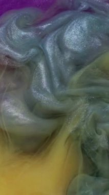 Dikey video. Dönen mürekkep. Su altı patlaması. Bulanık, mavi, sarı, renkli, parlak, parlak doku soyut arkaplanda yayılıyor..