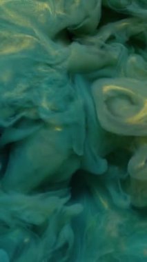 Dikey video. Parıltı sıçraması. Mürekkebi karıştır. Odaklanamayan mavi altın renkli su. Parlak akrilik parlak pigment. Soyut sanat arka planında dönen ıslak pigment..