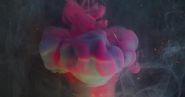 Bulut sıçraması. Mürekkep lekesi bulanıklığı. Cam ampulde renkli sıvı duman karışımı. Soyut siyah arka planda parlak pembe bir dere sızıntısı var..