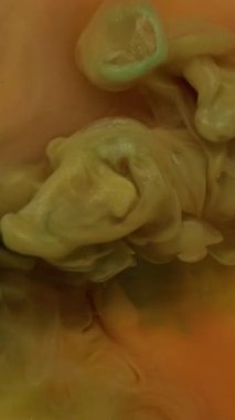 Dikey video. Buharlı arka plan. Boya rengi. Odaklanmamış sarı pembe duman dokusu su sıçrama sıvısı soyut sanatta yüzen sim sıvısı..