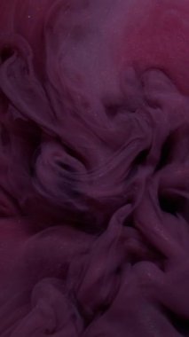 Dikey video. Buhar sanatı. Sis mürekkebi. Odaklanmamış mor renk akışı duman suyunda parlak kimyasal sıvı soyut koyu siyah arkaplanda yüzüyor..