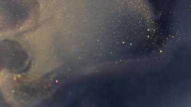 Parıltı yayılıyor. Boya dökülmüş. Parıldayan sanat parçacıkları su tozu akışı çözünüyor. Gri altın emülsiyon soyut arkaplan.