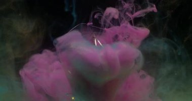 Su altı bulanık dumanı. Parlayan ampul. Aydınlatılmış cam çelenk soyut renk sıçraması. Siyah arkaplanda pembe mavi bulut akışı.