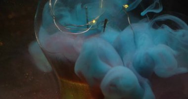 Haze akışı bulanık. Kırık ampul. Parlayan çelenge renk buharı dökülmüş. Kahverengi parıltılı, soyut, koyu arkaplanda mavi dumanlı boya var..