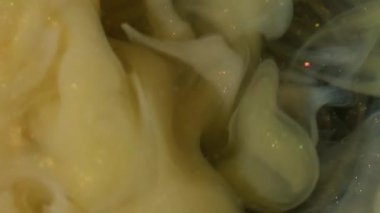 Duman girdabı. Köpüklü sıvı. Sarı bej, altın parıltılı boya akışı. Sanat sisi bulanık renk rengi su fantezi arkaplanı.