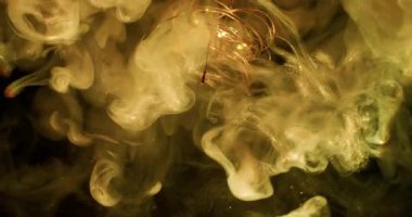 Pigment bulanıklığı. Parlak duman dalgası. Sarı altın parıldayan sis karışımı mürekkep sıvıda. Ampul çelengi rengi soyut siyah arkaplan.