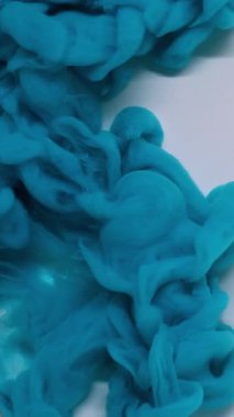 Dikey video. Mürekkep su sıçratır. Akışkan bulut. Soyut sanat arkaplana yayılan mavi renkli ıslak karışım sıvısı.