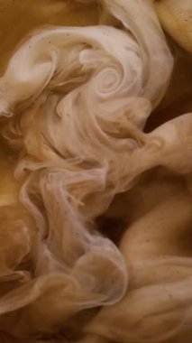 Dikey video. Bulut sıçraması. Mürekkebi karıştır. Odaklanamayan sarı bronz renkli su girdabı parçacıkları soyut sanat arka planında geziniyor.