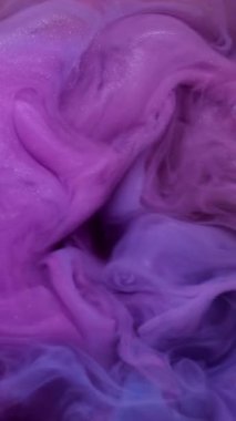 Dikey video. Sis dokusu. Mürekkep suyu. Bulanık pembe mavi renk buhar sıvı sıçrama parlak sıvı soyut arkaplana yayılıyor.