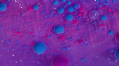 Akrilik parçacıklar karışır. Yüzen mürekkep. Pembe mor yağ damlaları ışıldayan parlak sıvılarda akıyor. Çoklu renk karışımı bulanık arkaplan.