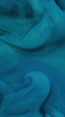 Dikey video. Boya sıçraması. Sigara arkaplanı. Odaklanamayan mavi renk suda dönüyor sanatın soyutlaması üzerine parlak ıslak parçacıklar..