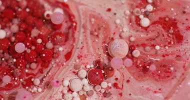Yağ kabarcıkları. Boya sıvısı. Odaklanmamış kırmızı pembe beyaz renkli ışıldayan parçacıklar soyut bokeh sanat arka planında yüzüyor..