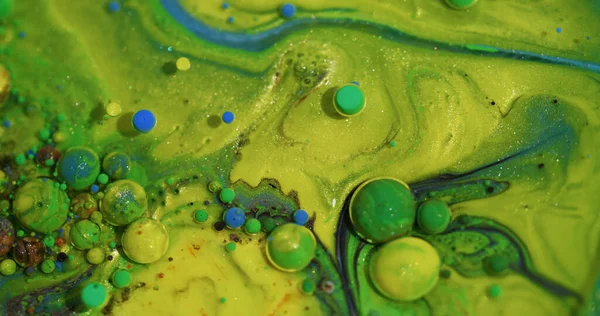 Renkli baloncuklar. Yağ sıvısı. Soyut akrilik bokeh arkaplan üzerinde yüzen sönük sarı mavi parlayan su parlak emülsiyonu.