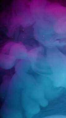 Dikey video. Duman patlaması. Boya akışı. Mor arkaplanda mavi pembe sıvı sis dalgası spreyi. Renkli neon rengi soyut pigment karışımı siyah bulanıklık.
