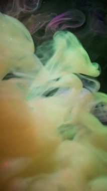 Dikey video. Hipnoz sıvısı. Renkli sis. Siyah, pırıl pırıl arka planda bir bulut girdabı. Gökkuşağı mürekkebi karışımı, parlayan, parlayan, odaklanmış sıvı..