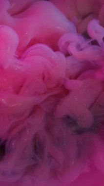 Dikey video. Renkli sis. Parıldayan dalga. Neon parlak boya sisi menekşe suyunda çözülüyor. Pembe duman soyut bulanık karışık arkaplan.