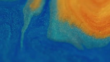 Parlak parçacıklar. Mürekkep emülsiyonu. Odaklanamayan mavi sarı renkli parıldayan su dokusu soyut sanat emaye arka planına yayılıyor..