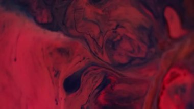 Sıvıyı karıştır. Akış sanatı. Su mermeri emülsiyonunda bulanık turuncu pembe boya soyut koyu siyah arka planda yayılan mavi lekeler..