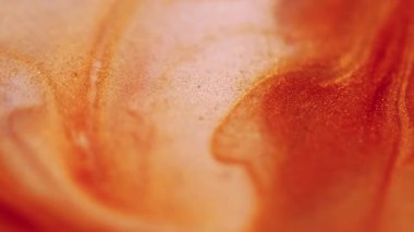 Işıldayan sıvı. Pırıl pırıl. Soyut akrilik zemin üzerine dökülen su lekelerinde çözünmüş sarı turuncu renkli boya..