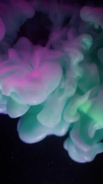 Dikey video. Duman patlaması. Boya akışı. Işıldayan arka planda yeşil mor sıvı sis dalgası spreyi. Renkli soyut pigment karışımı siyah bulanıklık.