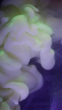 Dikey video. Duman patlaması. Boya akışı. Menekşe ışıldayan arka planda sarı bej renkli sis dalgası spreyi. Renkli soyut pigment karışımı siyah bulanıklık .