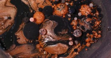 Mürekkep akışı. Parlak kabarcıklar. Odaklanmamış turuncu renk simleri soyut bokeh sanat arka planında yüzen siyah akrilik yağ suyu.