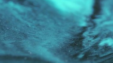 Köpüklü karışım. Mürekkep emülsiyonu. Odaklanamayan mavi renk parıldayan su akışı dokusu soyut sanat üzerine yayılıyor koyu siyah arkaplan.