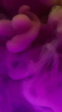 Dikey video. Parlak duman. Pigment akışı. Odaklanmamış arka planda pembe mor boya patlaması. Canlı renk soyut sis çözünen sanat bulutu.