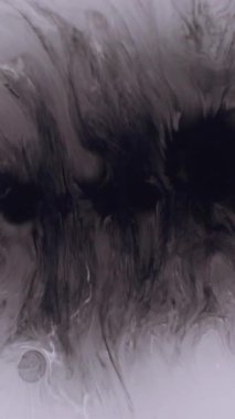 Dikey video. Boya lekesi. Sıçrama geçişi. Beyaz diş minesine siyah boya damlıyor. Monokrom sanat patlaması. Su soyut odaklanmış arka plan..