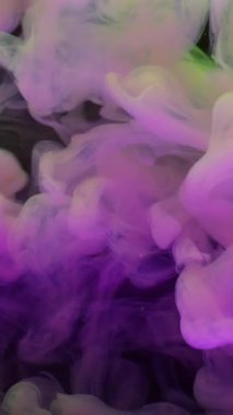Dikey video. Pigment damlası suyu. Boya patlaması. Pembe sarı neon boya çözünürlüğü. Soyut bulanık siyah arkaplanda renkli buhar karışımı.