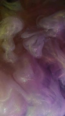 Dikey video. Duman patlaması. Işıldayan akış. Arka planda mor renkli sis dalgası spreyi. Renkli soyut pigment karışımı bulanıklığı.