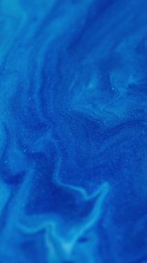 Dikey video. Boya sıvısı. Boya yayılmış. Mavi ışıltılı akrilik karışım soyut girdap. Renkli emaye sanat emülsiyon dalgası odaklanmış arkaplan.