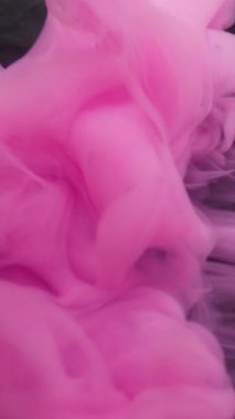 Vertical video. Color vapor. Ink shot. Pink pigment underwater dissolve. Haze liquid bright spray on black background abstract defocused flow.