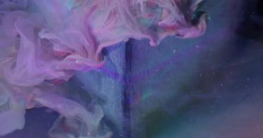 Parlak bir damla. Bulanık sıvı karışımı. Sanat küpüne pembe sıvı dökülmüş. Turkuaz renk pigment parçacıkları su altında soyut arkaplanı çözüyor.