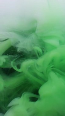 Dikey video. Sihirli duman. Boya karışımı. Yeşil beyaz girdaplı gizemli dere. Renk pigmenti çözünen sanat soyut siyah arkaplan yüzen dalga çözünürlüğü.