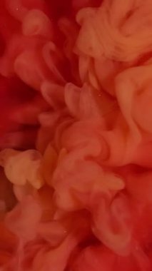 Vertical video. Smoke explosion. Fume paint. Orange wave pigment spill in red sparkling water. Color stream dye defocused dissolve abstract background.