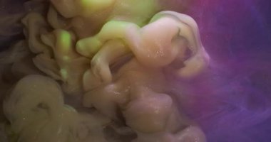 Su altı sisi. Sıçrama sanatı. Odaklanmamış mavi mor renkli mürekkep desenli simli sıvı soyut pembe arka planda yüzüyor..