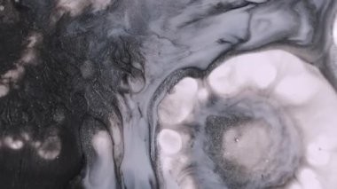 Dökülen mürekkep. Boya damlası. Soyut akrilik mavi zemin üzerinde yüzen koyu siyah beyaz yuvarlak sıvı pigment..