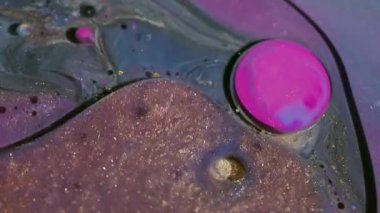 Parlak mürekkep akışı. Parıldayan baloncuklar. Odaklanmamış pembe turuncu renkli damlacık simli akrilik yağ suyu soyut sanat arka planında yüzüyor..