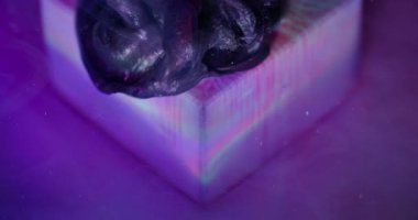 Sızdıran sim. Odaklanmamış sanat sıçraması. Işıldayan mürekkep menekşe siyah akış küpü. Suyun soyut arka planında mor boya çözünüyor.