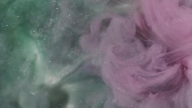 Parıldayan mürekkep. Işıl ışıl parlayan boya. Odaklanmamış pembe mavi renk su sıçrama pigmenti soyut beyaz sanat arka planına yayılıyor.