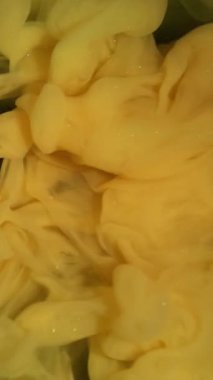 Dikey video. Sihirli duman. Boya karışımı. Sarı yeşil kıvrımlı gizemli dere. Renk pigmenti çözünen sanat soyut arkaplan titreşimli dalga çözünürlüğü.